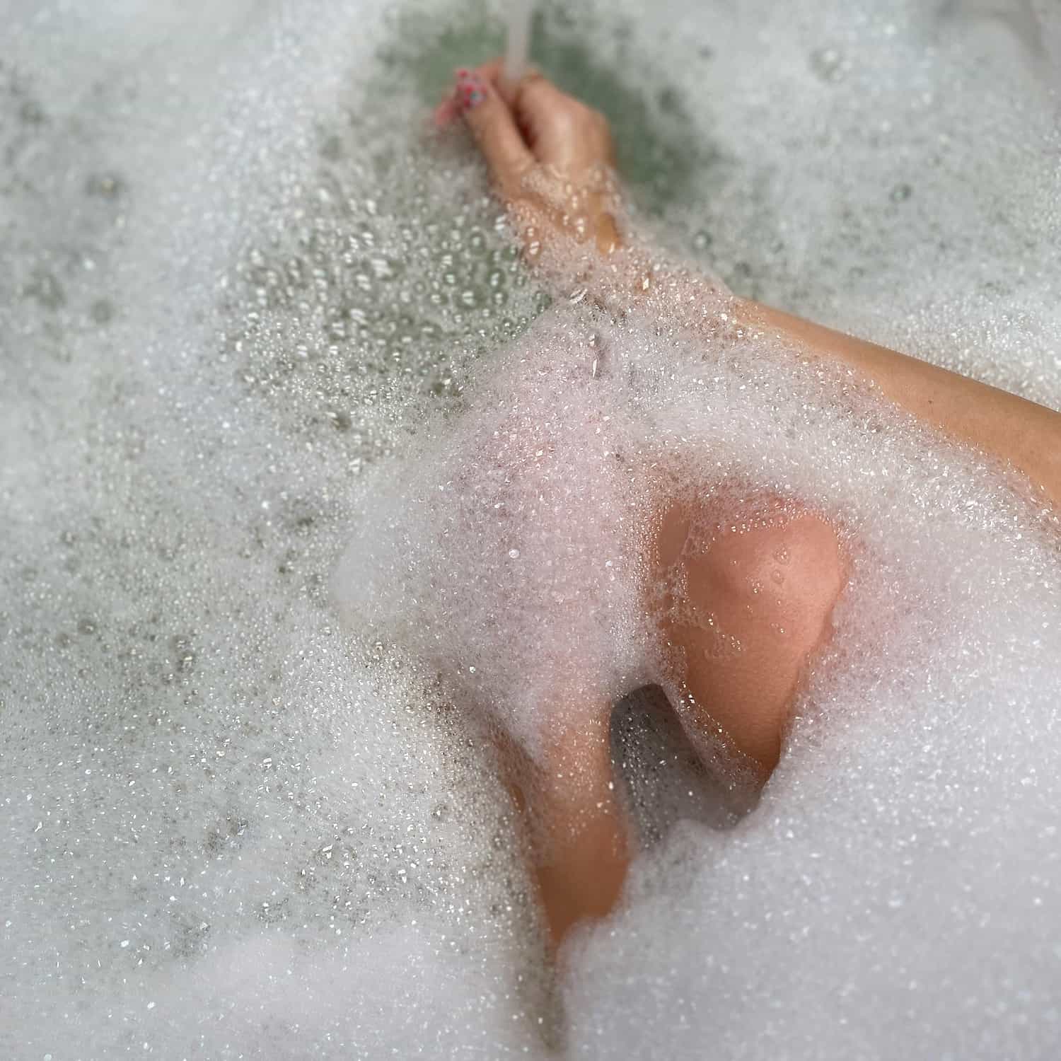 Un corps féminin prend un bain mousseux
